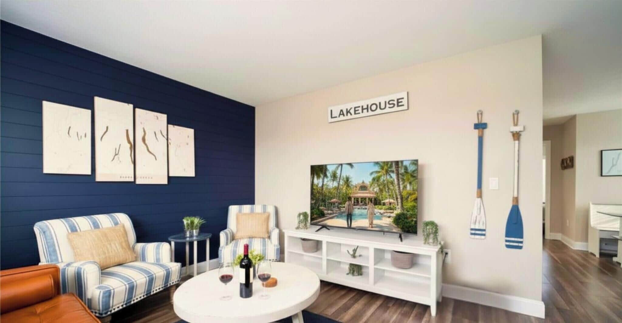 A living room with a blue wall, a striped sofa, a white entertainment unit, and a television displaying a pool scene.