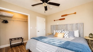 Une chambre à coucher avec un lit, un ventilateur de plafond, une tête de lit en bois et une petite table sur laquelle est posée une lanterne.
