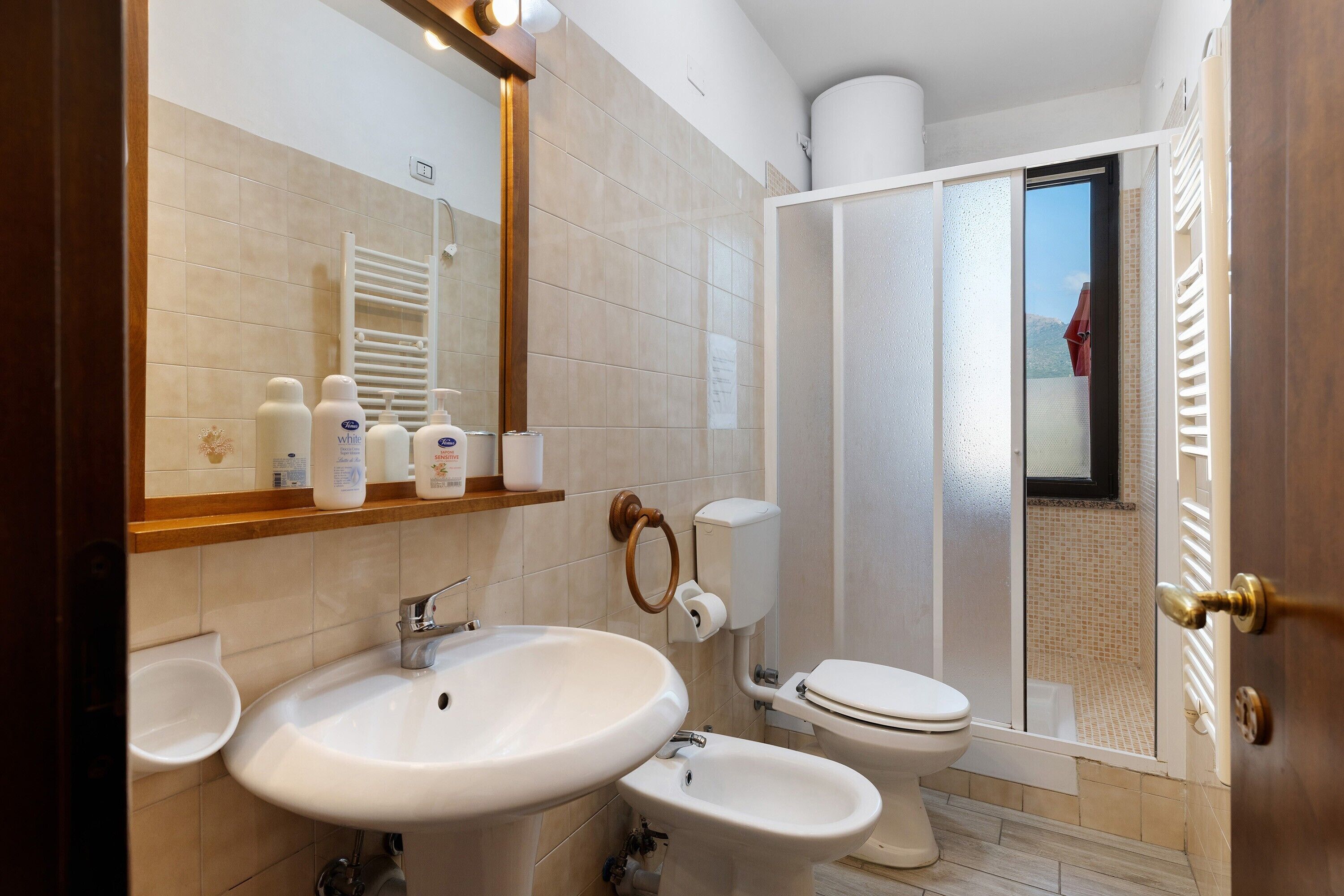 Ein modernes Badezimmer mit großem Spiegel, zwei Waschbecken, Toilette und Duschbereich.