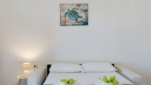 Habitación de hotel con cama, dos almohadas, mesita de noche con lámpara y dos toallas con lazos verdes.