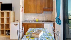 Una cocina compacta con armarios de madera, horno empotrado y comedor con mesa lista para dos personas.