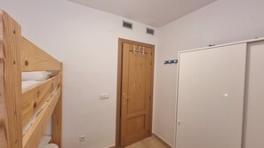 Ett rum med en säng i våningssäng av trä, en trädörr och en vit garderob.