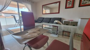 Ein Zimmer mit Esstisch, Stühlen, einer Couch, einem Spiegel und einem fenster mit Vorhängen.