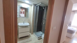 Ein Badezimmer mit Waschbecken, Spiegel, Duschkabine und Toilette.