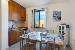 A compact kitchen with wooden cabinets, a built-in oven, and a window with curtains.