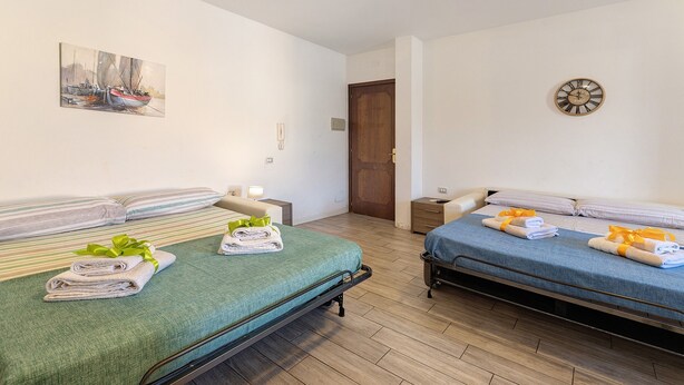 Une chambre d’hôtel avec deux lits, un tableau au mur, une horloge et un plancher en bois.