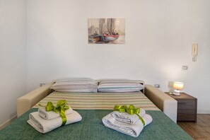 A hotel room with a bed, pillows, a painting on the wall, a bedside lamp, and a nightstand.