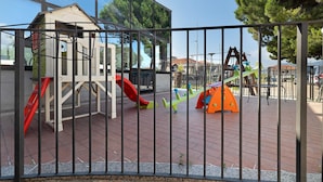 Une aire de jeux avec un toboggan, une structure d’escalade et une balançoire.