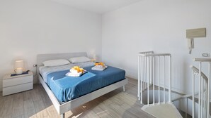 Una camera d'albergo con un letto, comodini, una lampada e un termosifone.
