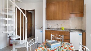 Una cucina compatta con mobili in legno, lavastoviglie integrata e zona pranzo con tavolo apparecchiato per due.