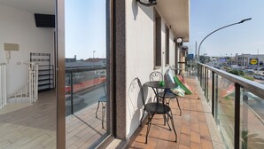 Un balcone con tavolo e sedie, una telecamera di sicurezza e vista sulla strada.