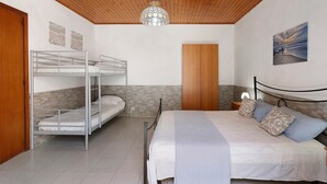Une pièce avec des lits superposés, un plafond en bois, un mur en pierre, un lit avec des oreillers et un tableau accroché au mur.