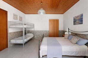 Une pièce avec des lits superposés, un plafond en bois, un mur en pierre, un lit avec des oreillers et un tableau accroché au mur.