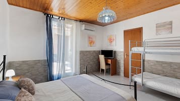Ein Zimmer mit einem Etagenbett, einem Schreibtisch mit Stuhl, einem Fernseher und Bildern an den Wänden.