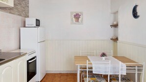 Une cuisine compacte équipée d’un four à micro-ondes, d’un réfrigérateur, d’un four et d’une table à manger avec des chaises.