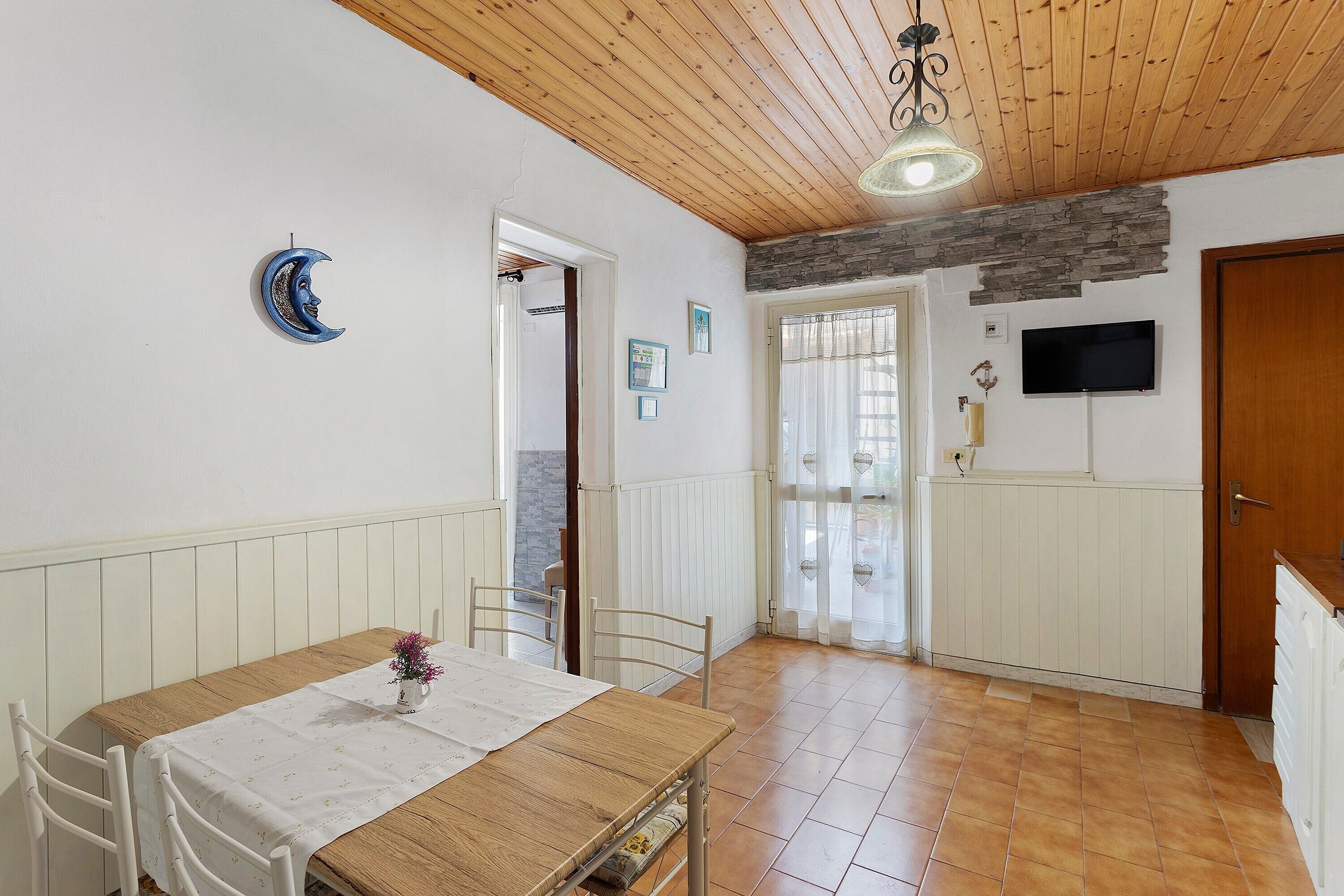 Ein Essbereich mit Holztisch und Stühlen, einem Deckenventilator und einer Steinwand.