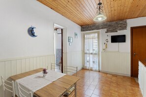 A dining area with a wooden table and chairs, a ceiling fan, and a stone wall.