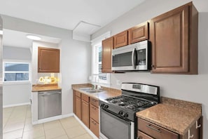 A kitchen with wooden cabinets, stainless steel appliances, and a granite countertop. - 1918 Charm Meets Modern  OSU-Close Gem (Columbus)