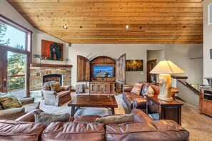 A cozy living room with a stone fireplace, leather sofas, and a television. - Tahoe City Retreat | Lake View & Hot Tub (Tahoe City)