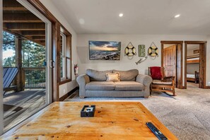 A cozy living room with a wooden coffee table, a sofa, and a painting of a sunset over a lake. - Tahoe City Retreat | Lake View & Hot Tub (Tahoe City)