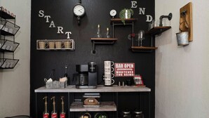 Una zona de cocina con una cafetera, un reloj y un cartel que dice 'BAR OPEN'.