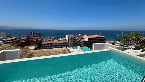 Ein Pool mit freiem Blick auf den Ozean und Gebäuden im Hintergrund.