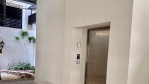 Ein modernes Interieur mit Holzboden, weißer Wand und einer Metall-Aufzugskabine.