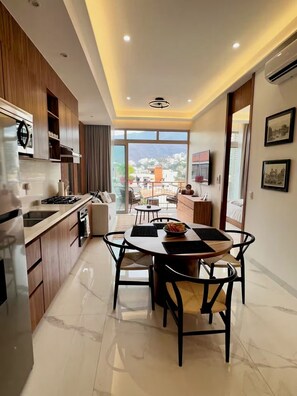 A modern kitchen with a dining area, large windows, and a view of the city. - Luxury & Modern Penthouse in the Heart of Zona Romántica - Walk Everywhere! (Puerto Vallarta)