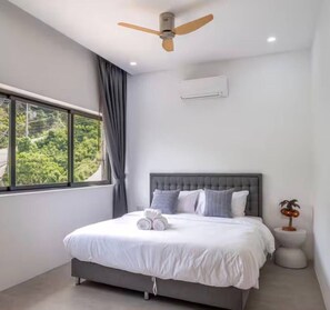 Ein modernes Schlafzimmer mit einem Bett, einem Deckenventilator, einem Fenster mit Vorhängen und einem Nachttisch mit einer Lampe.