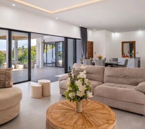 Ein modernes Wohnzimmer mit einer Couch, einem Couchtisch und einem Essbereich mit Tisch und Stühlen.
