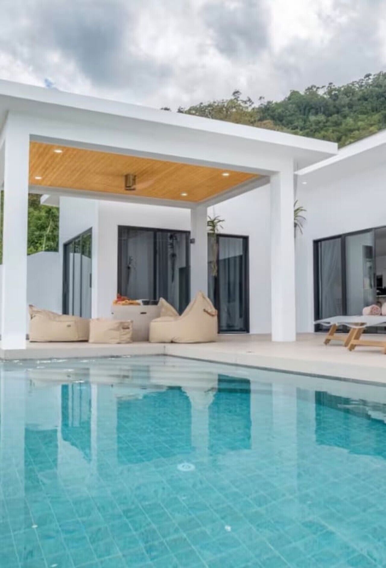 A modern poolside area with a covered seating area and a clear blue pool.