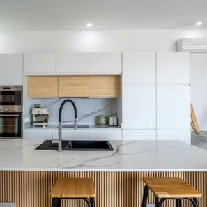 A modern kitchen with a central island, wooden cabinets, and a built-in oven. - Villa Orchid 3BR Seaview villa with private pool (Chaweng)