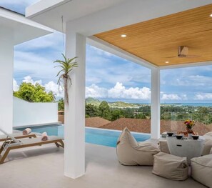 A modern outdoor lounge area with a pool, seating, and a view of the landscape.