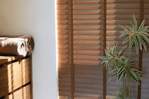 A room with a wooden bench, a rolled towel, and a plant against a wall with horizontal blinds. - Luxury 6-Bedroom Villa with Sea View and Gym (Chaweng)