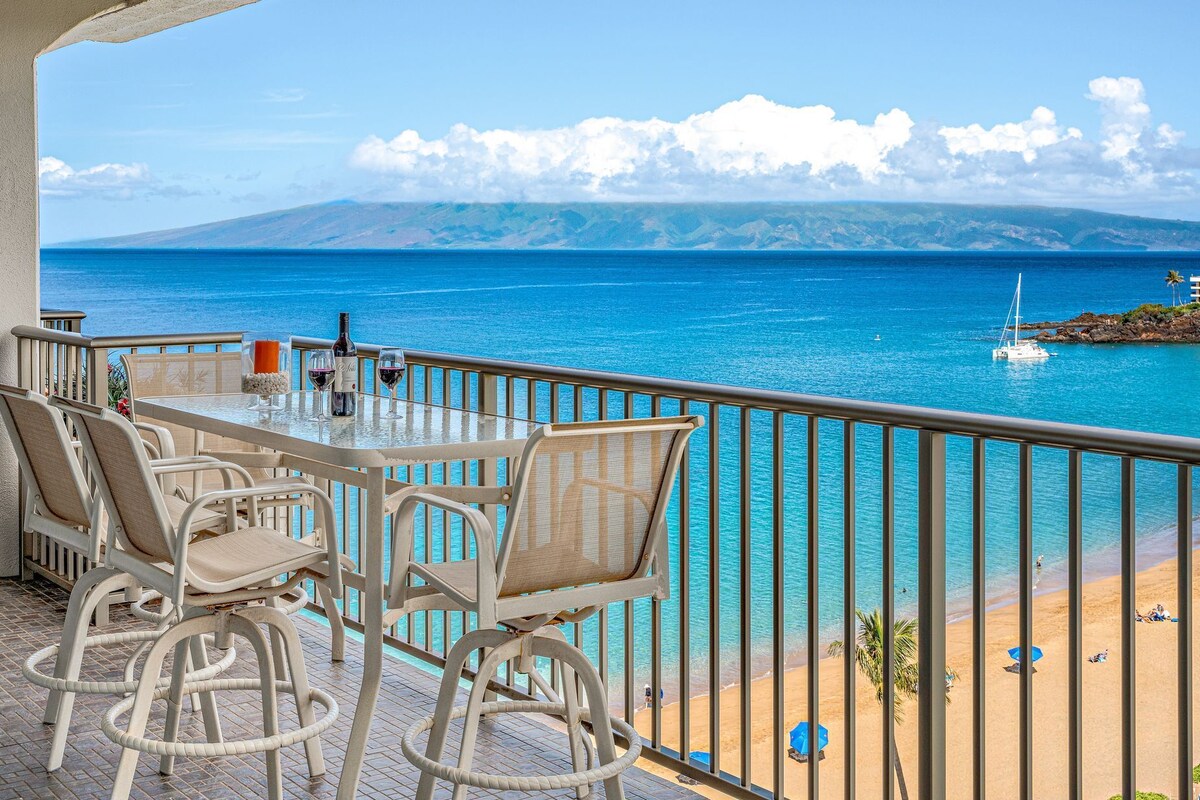 Ein Balkon mit Tisch und Stühlen mit Blick auf Strand und Meer.