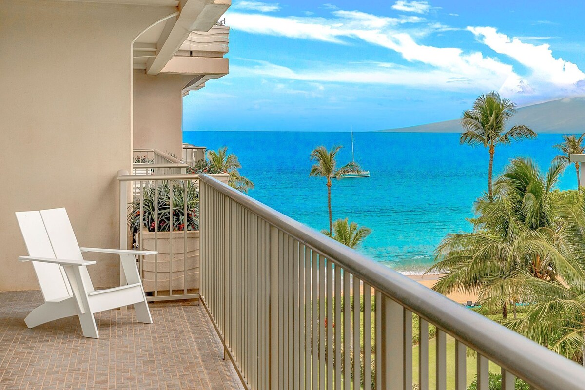 Ein Balkon mit einem weißen Stuhl, Blick auf das Meer und ein Segelboot in der Ferne.