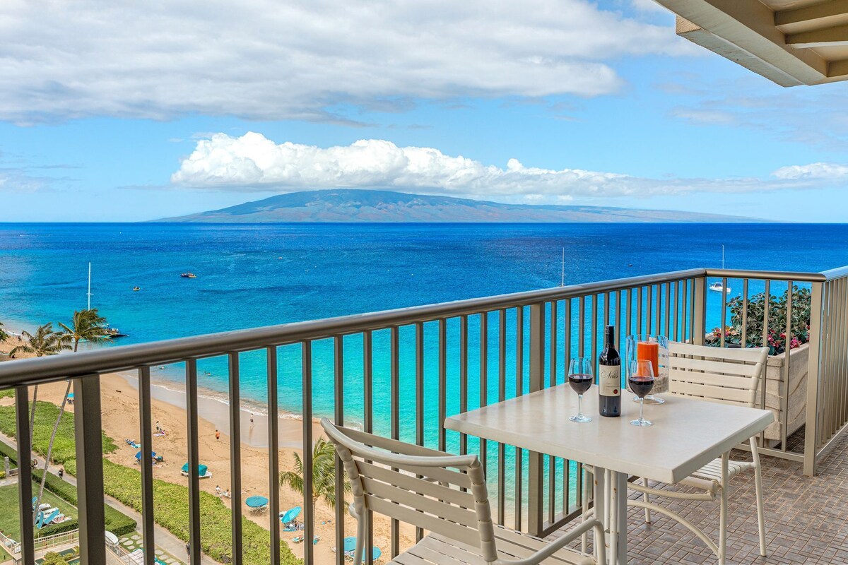 Ein Balkon mit Tisch, Stühlen und Blick auf das Meer und den Strand.