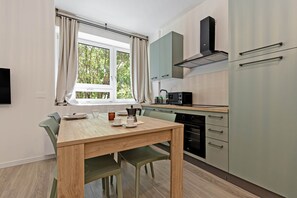 A compact kitchen with a dining table, chairs, a coffee maker, and a built-in oven. - Salvia Atmosfera Naturale, a studio apartment in Bergamo (Bergamo)