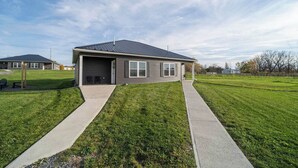 A single-story house with a garage, a covered porch, and a well-maintained lawn.