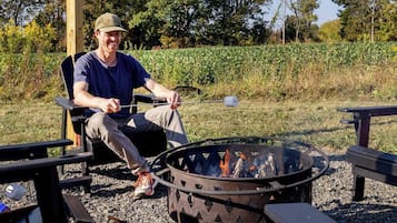 A person seated at a table with a fire pit in front of them.