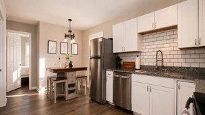 A kitchen with white cabinets, stainless steel appliances, and a granite countertop.
