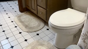Un baño con inodoro, lavamanos, espejo y toallero.