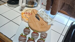 Una encimera de cocina con una cafetera, una taza, un plato de fresas bañadas en chocolate y un cortador de galletas de madera.