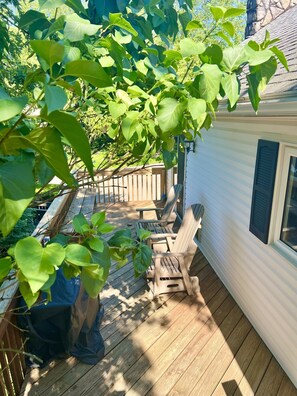 A wooden deck with outdoor furniture, a covered area, and a house with a window. - Romantic Queen Cottage with Jacuzzi & Fireplace (Berlin)