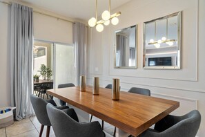 Ein moderner Essbereich mit Holztisch, grau gepolsterten Stühlen und Pendelleuchten.