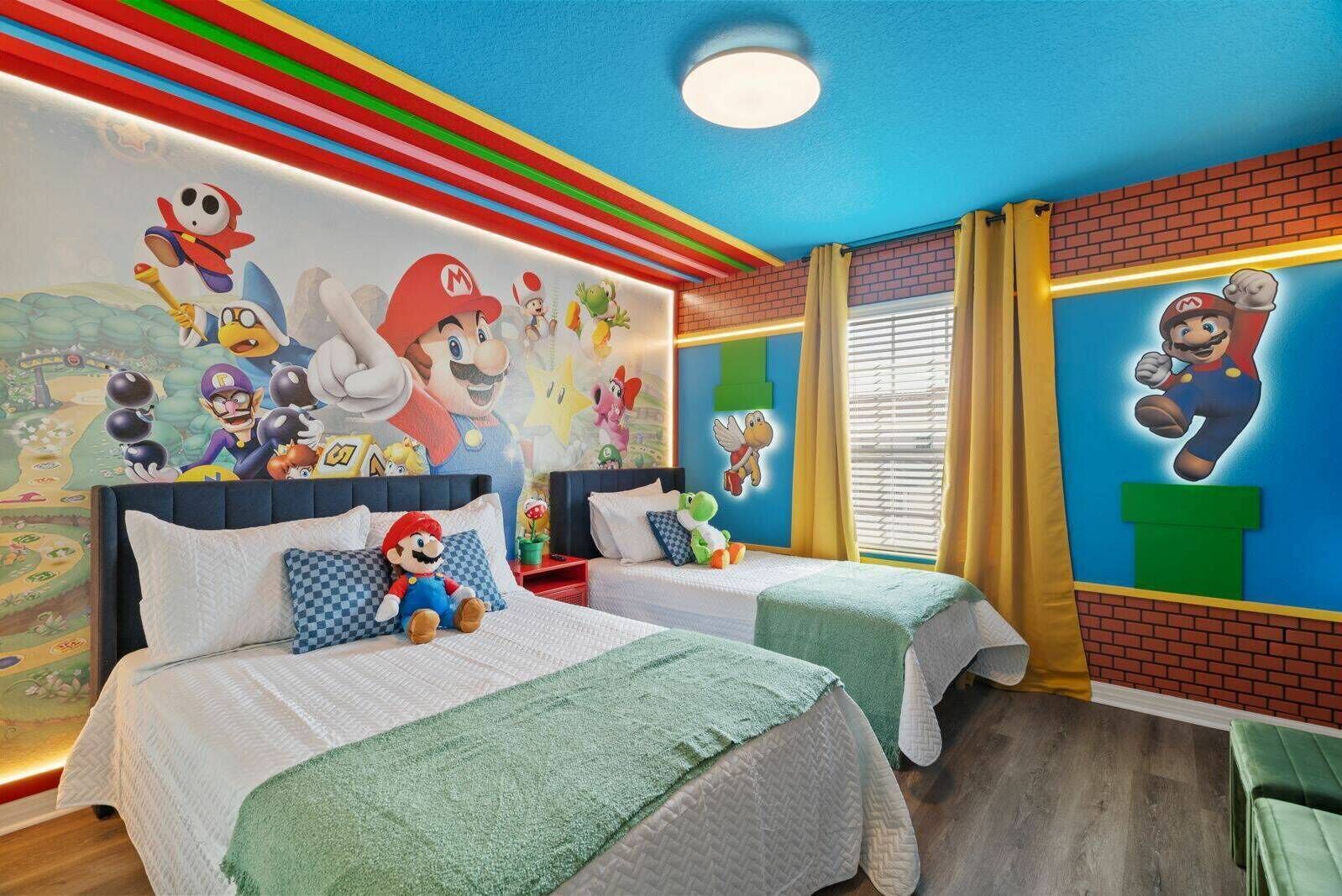 Une chambre d’hôtel avec deux lits, des peintures murales colorées et une décoration sur le thème de Mario.