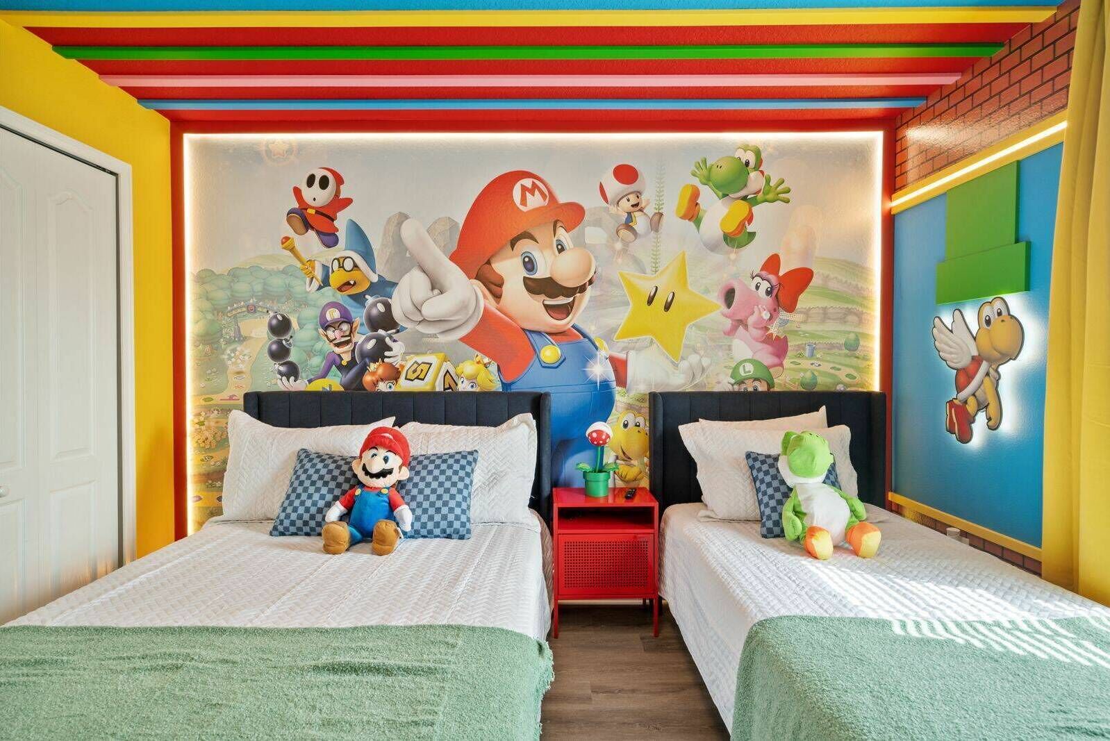 A room with two beds, colorful wall art, and a Mario plush toy.