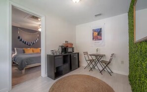 Un espace de vie compact comprenant un lit, une kitchenette, un coin repas et un mur végétal décoratif.
