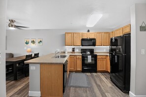 Una cocina moderna con armarios de madera, un refrigerador negro, un microondas y una estufa.