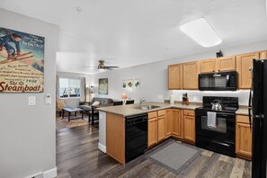 A modern kitchen with wooden cabinets, a black refrigerator, and a dishwasher. - First Tracks at Wildhorse | Gondola + Hot Tubs (Steamboat Springs)